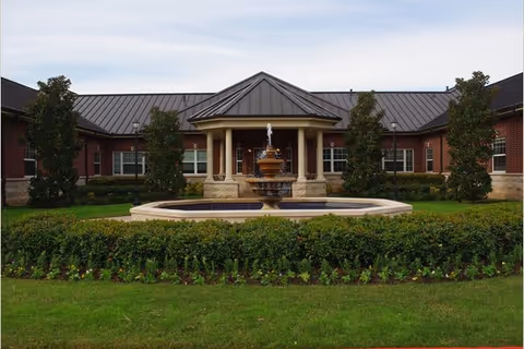 Front view of Riverstone Memory Center with a circular fountain and landscaped courtyard.