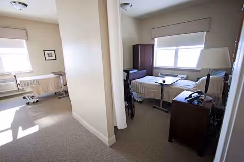 Two adjoining patient rooms with beds, desks, and a central partition.