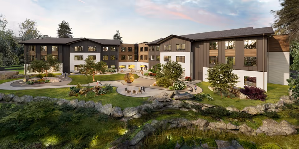 A modern senior living campus with connected buildings and a landscaped courtyard along rocky waterfront.