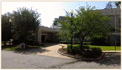 Front entrance to The Harbor at Hickory Hill senior living, with driveway and trees.