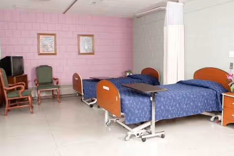Shared patient bedroom at Woodland Care CBRF with two beds and a privacy curtain.