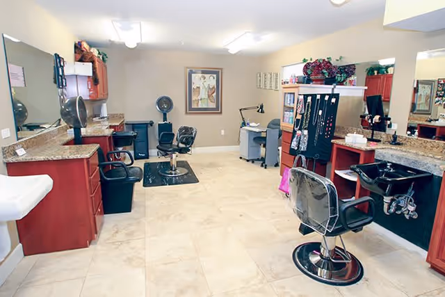 Bright salon-style interior with styling chairs, mirrors, sinks, and cabinetry.