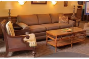 Warmly lit living room with a sofa, two armchairs, a wooden coffee table and lamps.