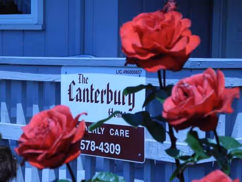 Blue building exterior with The Canterbury Home sign and red roses.