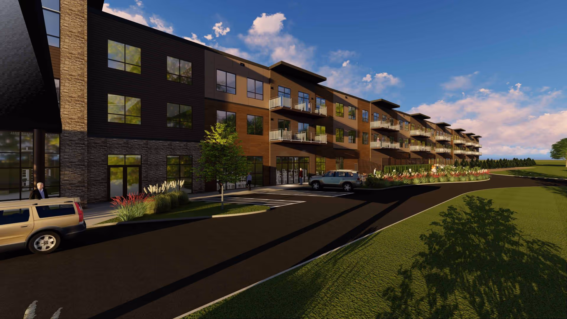 Exterior view of a modern three-story senior living facility building with balconies, large windows, and landscaped surroundings under a partly cloudy sky. There are a few parked cars and a person near the entrance.