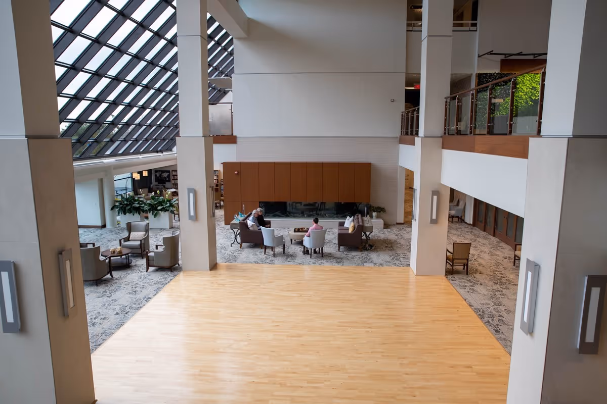 Spacious two-story lobby with a seating area, large slanted skylight windows, and a polished wood floor.