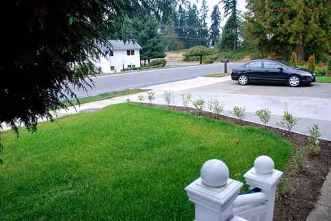 Front exterior of the facility with a green lawn, driveway, and a parked car.