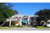 Front view of Bayou Gardens Assisted Living facility with entrance, sign, and landscaping.