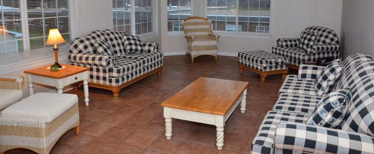 Sunroom-style living room with matching black-and-white checkered sofas and chairs around a wooden coffee table and large windows.