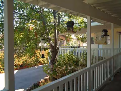 Covered outdoor walkway at Lakeside Manor with trees and white railing.