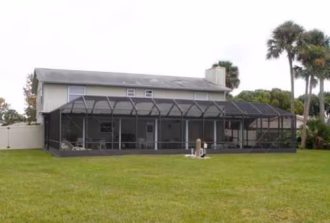 Two-story building with a large screened-in patio and green lawn.