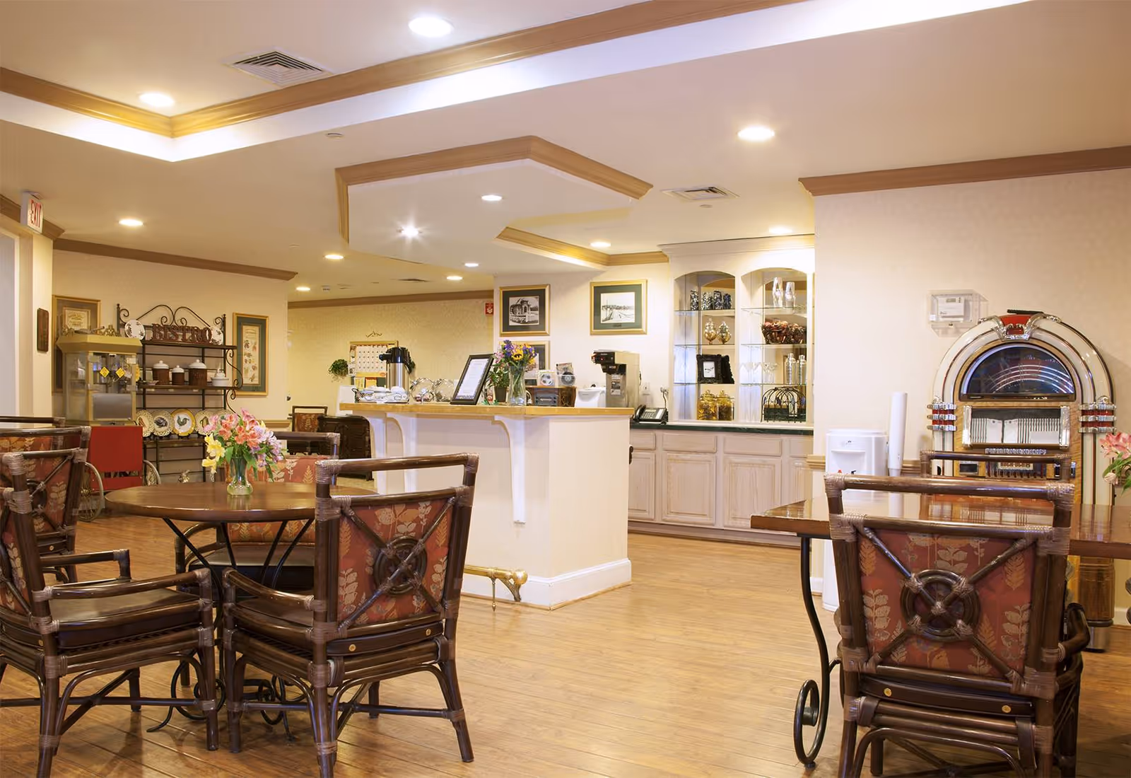 Well-lit communal dining/lounge area with round tables and chairs, a service counter and a decorative jukebox.