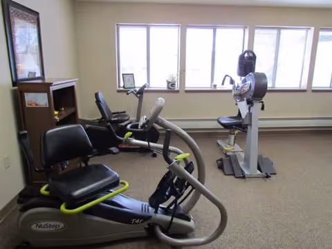 Interior fitness room with stationary bikes and exercise equipment by large windows.