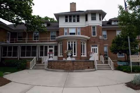 Front exterior view of Oak Crest Residence & Atrium Apartments with brick building and curved entry.