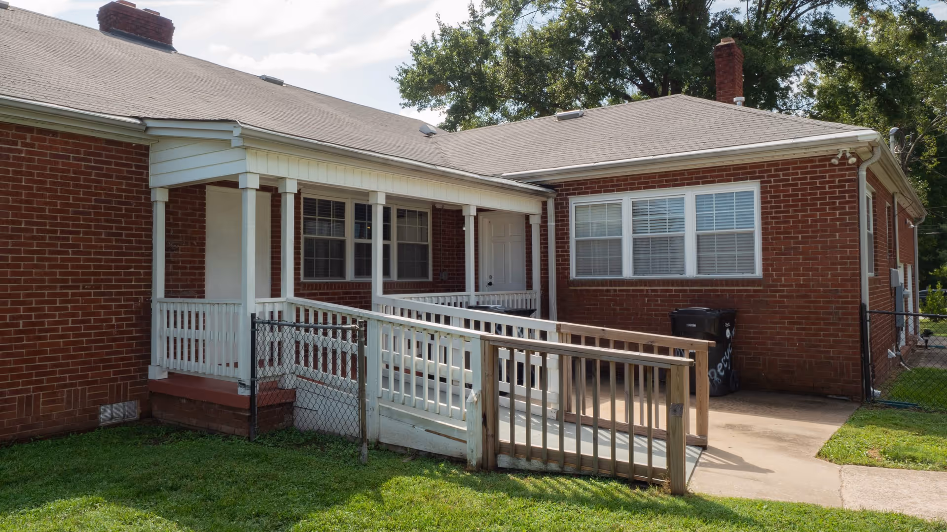 Brick senior living facility with a white porch, ramp, and front entrance.