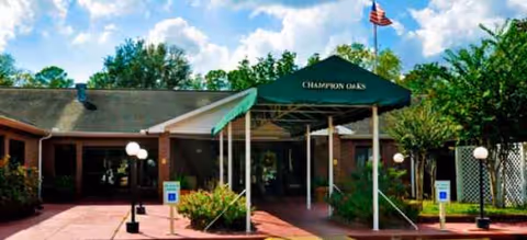 Exterior entrance to a brick building with a green canopy and surrounding landscaping.