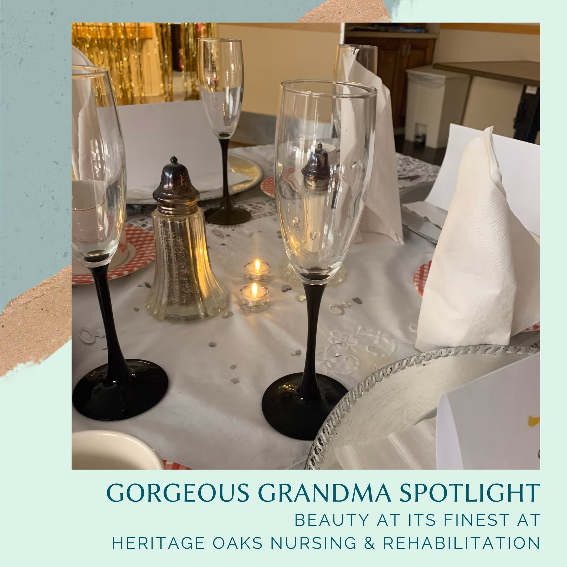 A close-up view of a dining table set with black-stemmed champagne flutes, folded white napkins, a salt shaker, small lit candles, and decorative confetti on a white tablecloth.