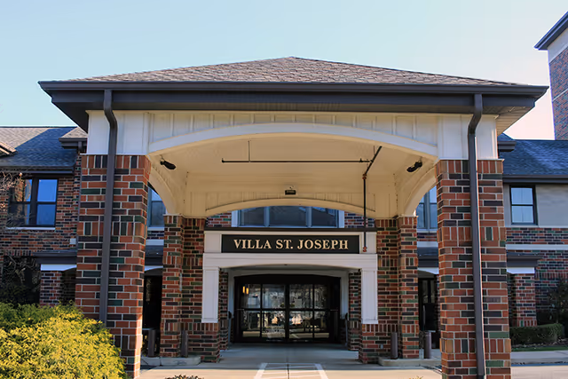 Exterior view of the Concordia at Villa St. Joseph entrance with a brick portico and glass doors.