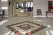 Entrance lobby with a decorative tiled floor, seating, and a view into a dining area through glass doors.