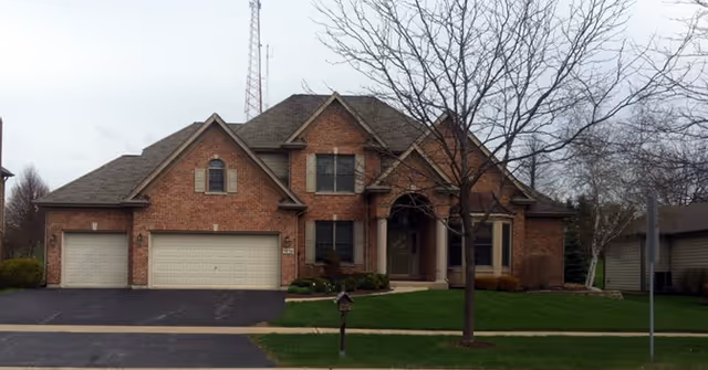 A brick residential building with a well-maintained front yard.