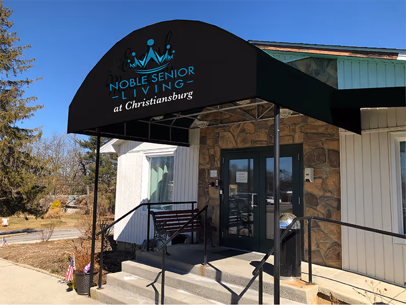 Exterior entrance of Noble Senior Living at Christiansburg with stone facade and wheelchair ramp.