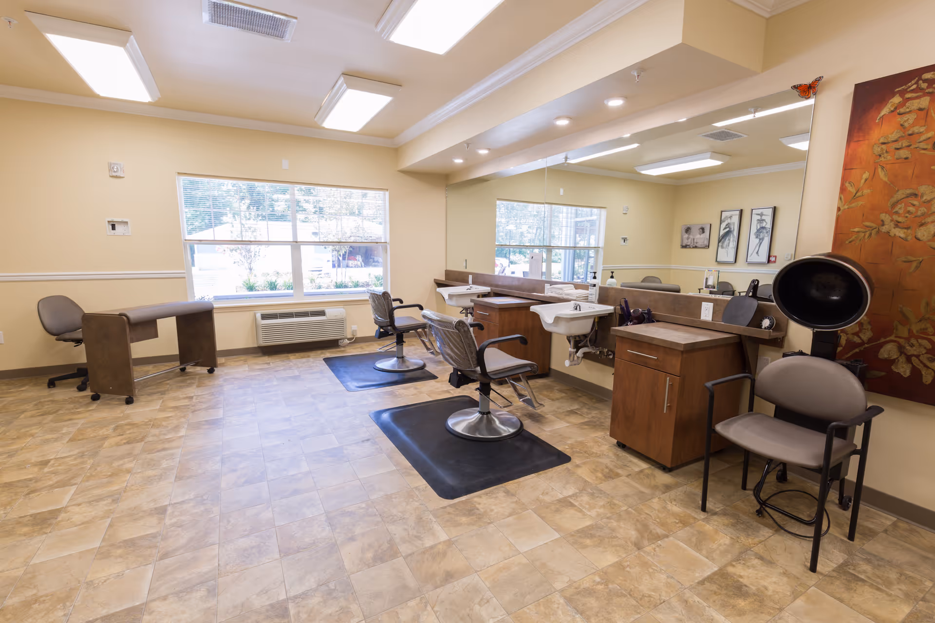 Bright salon room with styling chairs, mirrors, sinks and a hair dryer in a senior living facility.
