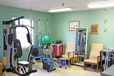 Rehabilitation exercise room with workout machines, a ball, mirrors, and chairs.