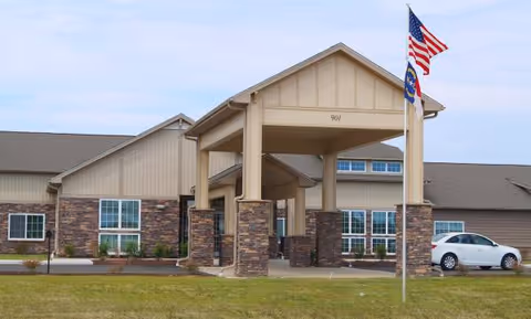 Front view of Eagle's Pointe senior living facility entrance with flags