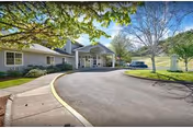 Front entrance of an assisted living building with a covered portico, circular driveway, and landscaped grounds.