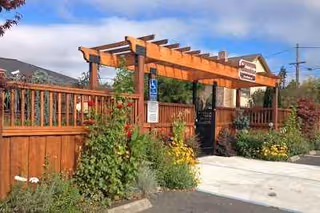 Exterior view of Mirabel Lodge with wooden pergola, fence, and landscaped entry.