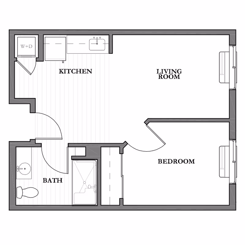 Architectural floor plan of a one-bedroom assisted living unit showing a kitchen with washer and dryer, a living room, a bedroom, and a bathroom with a toilet, sink, and bathtub.