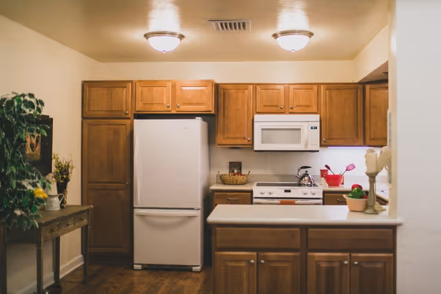 A warm kitchen with wooden cabinets, white appliances, and a central island.