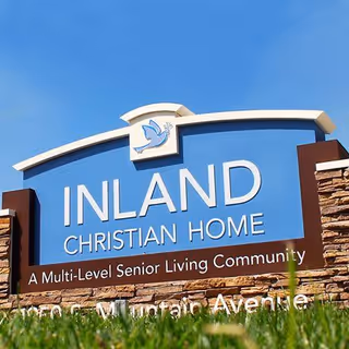 Outdoor sign for Inland Christian Home, a multi-level senior living community, with a blue sky background and grass in the foreground.