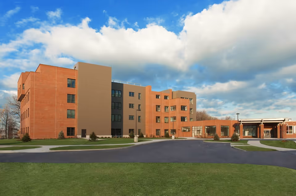 Exterior view of a multi-story brick senior living facility with a curved driveway.