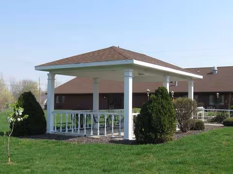 Outdoor gazebo with white columns and green lawn in front of Oakbrook Village facility.