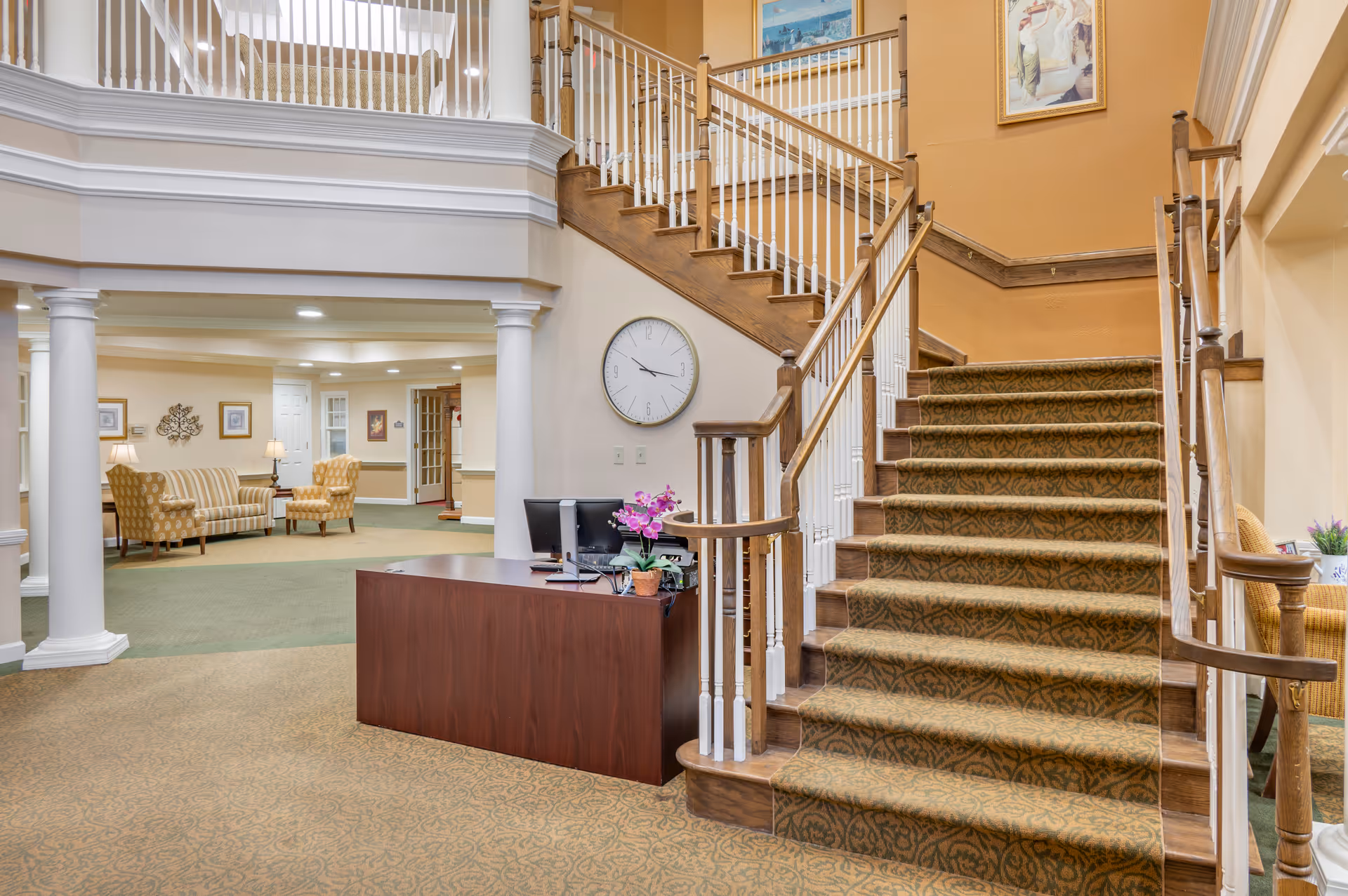 Lobby interior featuring a reception desk, a carpeted staircase, and a seating area.