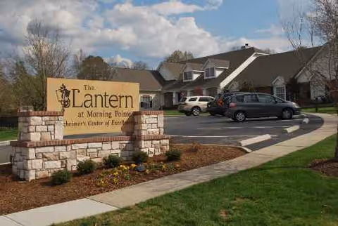 Exterior view of The Lantern at Morning Pointe Alzheimer's Center with sign and cars.
