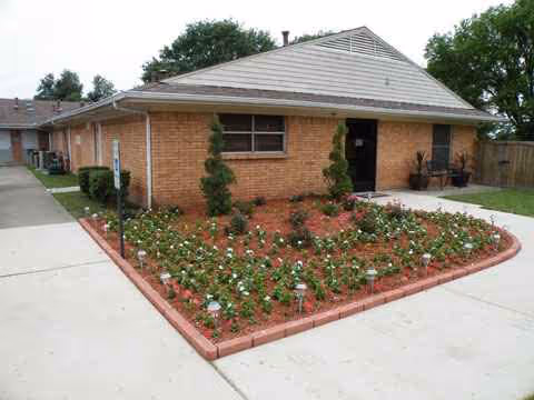 Single-story brick care center with curved flower beds, shrubs, and a concrete sidewalk.