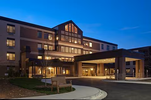 Exterior view of New Perspective Senior Living Brookfield entrance with illuminated lobby and walkway.