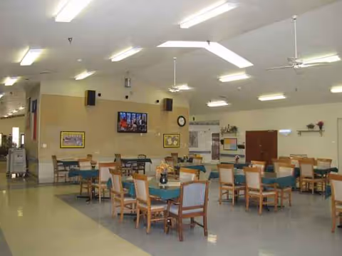 A spacious dining hall with multiple round tables and teal tablecloths.