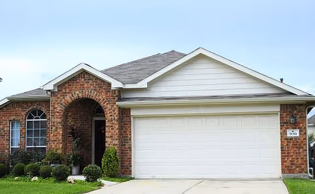 Front view of a brick house with a two-car garage and well-kept lawn