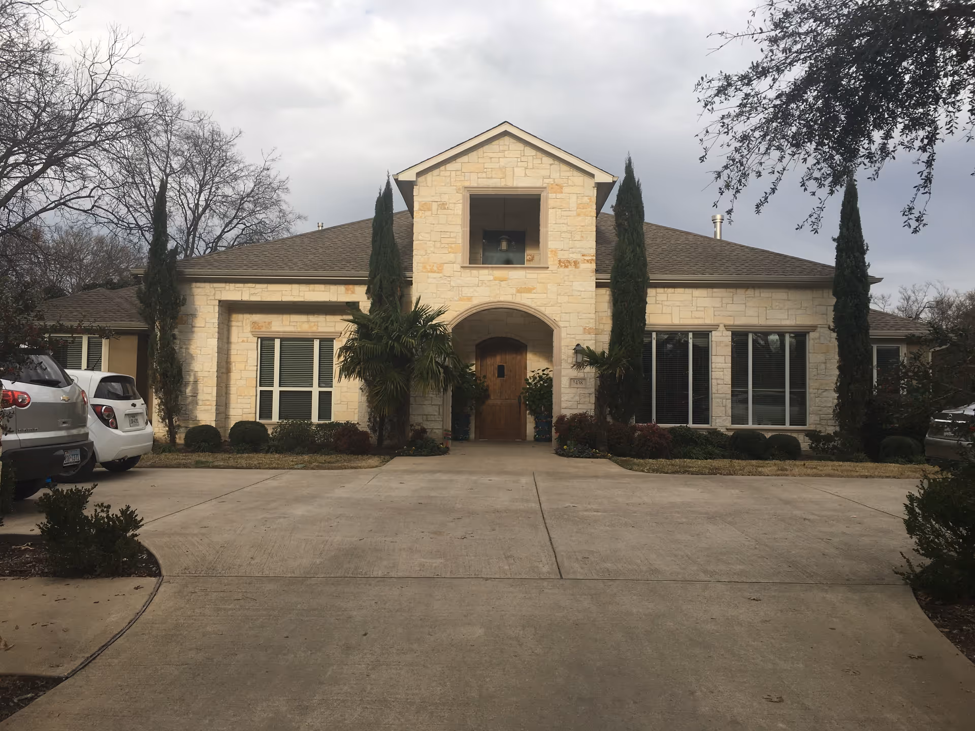 Stone-faced senior living facility exterior with arched entrance and parked cars