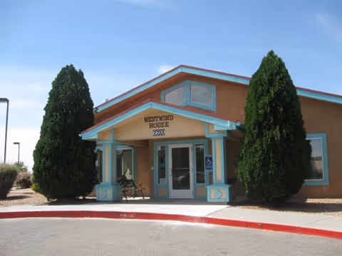 Front view of Westwind House Assisted Living with turquoise trim and two trees.