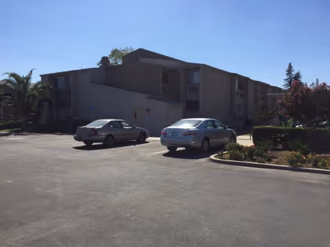Exterior view of Vintage Gardens Assisted Living Community with cars in parking lot.