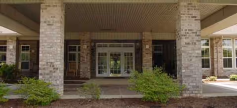 Front entrance of Brookdale Eden, brick columns, glass doors, and landscaped walkway.