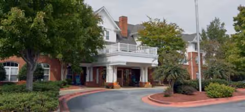 Exterior view of Charter Senior Living of Vinings with a circular driveway and green landscaping.