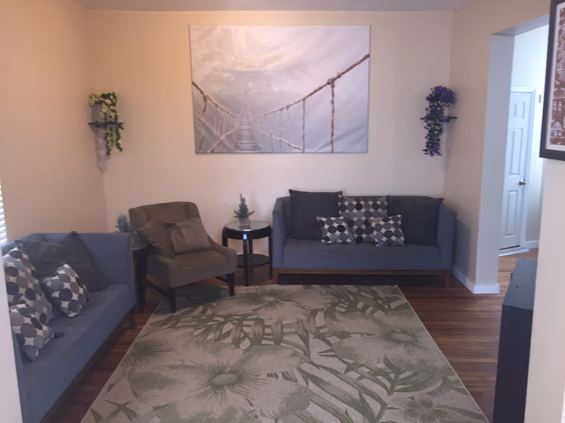 Cozy living room with two sofas, an armchair, patterned throw pillows, a side table, rug and wall art.
