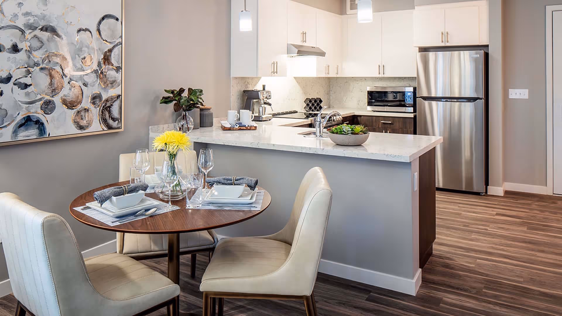 Open-plan kitchen with a marble-topped island and a small dining table set for four.