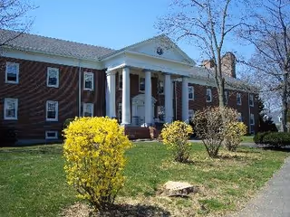 Brick colonial-style building with white columns and a front entrance.