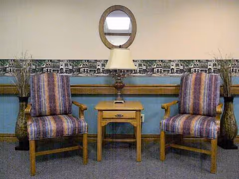 Two striped armchairs flank a small wooden table with a lamp in a lounge.